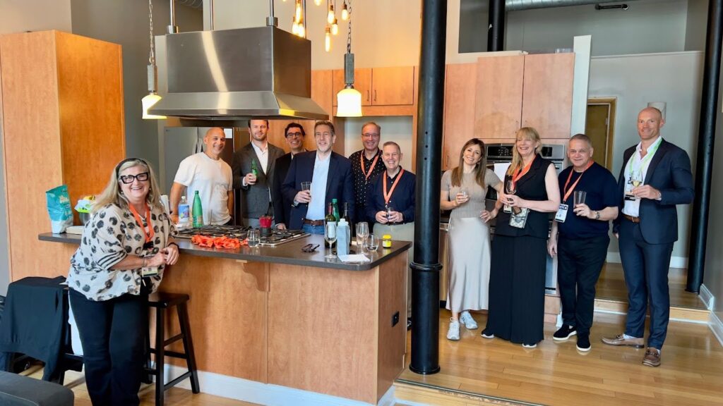 The GAIN team gathered in a modern kitchen, smiling and holding drinks during a casual networking or social event.