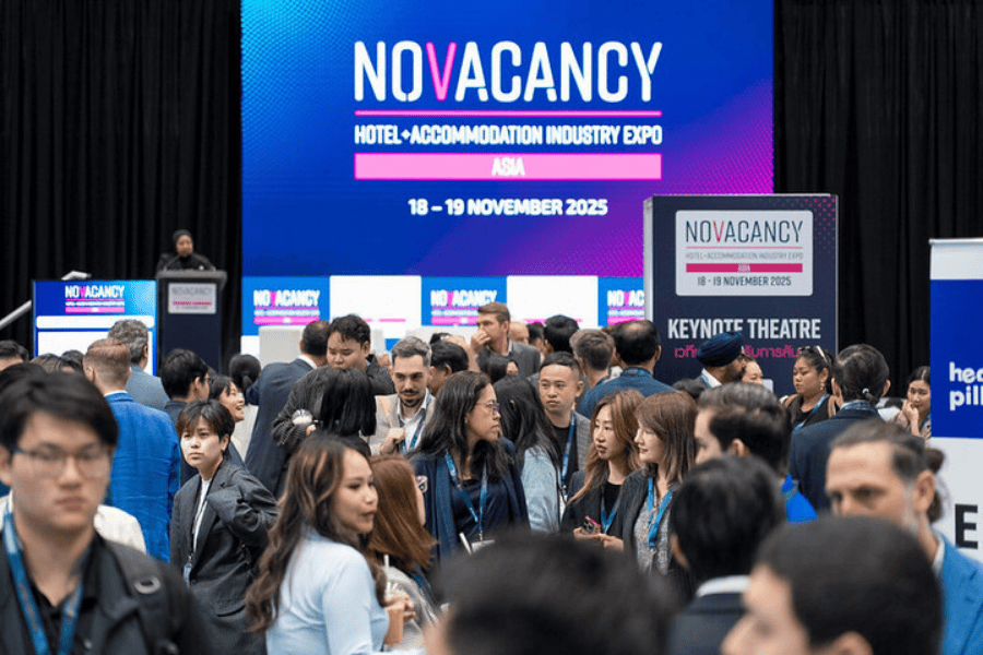 A large crowd of attendees networking in front of a bright NOVACANCY Hotel + Accommodation Industry Expo 2025 stage backdrop.
